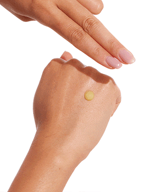 A hand displays a dab of BondiSandsEU Baby Face Retinol Serum—ideal for youthful skin—on the back, as the other hand's fingers prepare to spread it. The background is white.