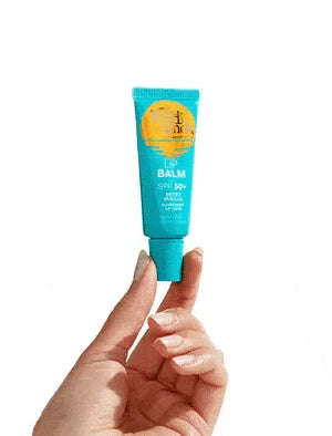 A hand holds a turquoise Bondi Sands Europe lip balm tube with SPF 50+ against a white background. The label's yellow and white text highlights sun protection. An ideal pick for your SPF Besties Bundle.