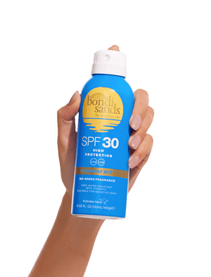A hand holds a blue can of BondiSandsEU SPF 30 Everyday Sunscreen Aerosol Mist with yellow and white text against a plain white background, offering UVA/UVB protection for daily use.