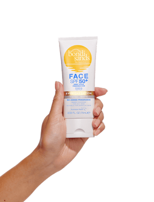 A hand holds a white tube of BondiSandsEU SPF 50+ Everyday Matte Tinted Face Lotion with gold and blue labeling against a plain white background.