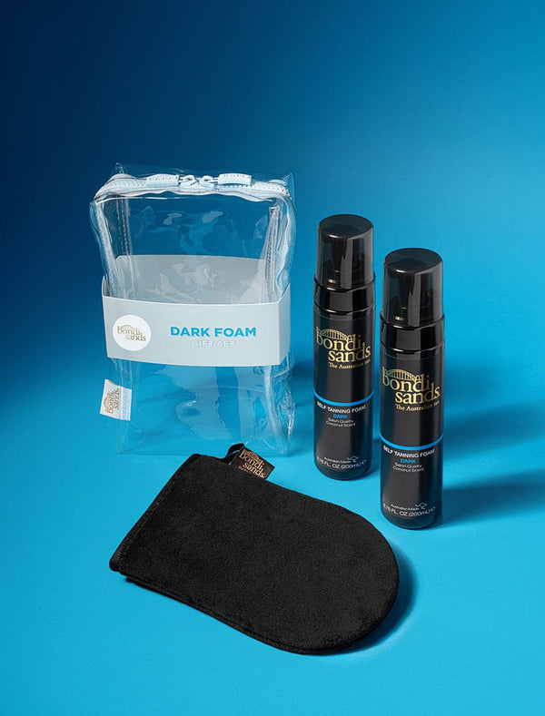 The BondiSandsEU Dark Foam Gift Set includes two bottles of self tanning foam and a black application mitt in a clear bag, all shown on a blue background.
