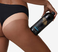 A person in black underwear displays a large bottle of BondiSandsEU Salon Solution Ultra Dark, highlighting a noticeable tan line on their upper thigh and buttock against a plain white backdrop to showcase the professional tanning results.
