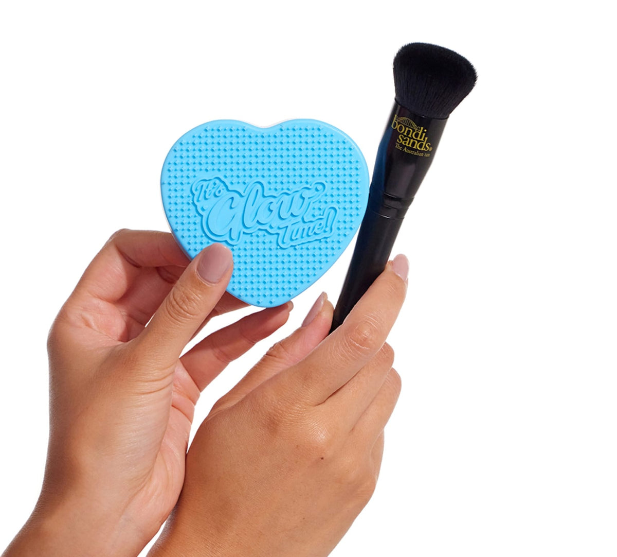 A person holds the BondiSandsEU Self Tan Contour Kit—featuring a blue heart-shaped cleaner and contour brush—against a white background, ideal for creating a flawless bronzed glow.