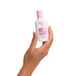 A hand holding a white bottle with a pink cap labeled BondiSandsEU Baby Face Retinol Serum, designed to reduce fine lines for youthful-looking skin, against a plain white background.