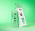Two green BondiSandsEU Emerald Technocolor Self Tanning Face Serums are displayed on a green background, both designed for deep olive tone and ideal for blemish control.