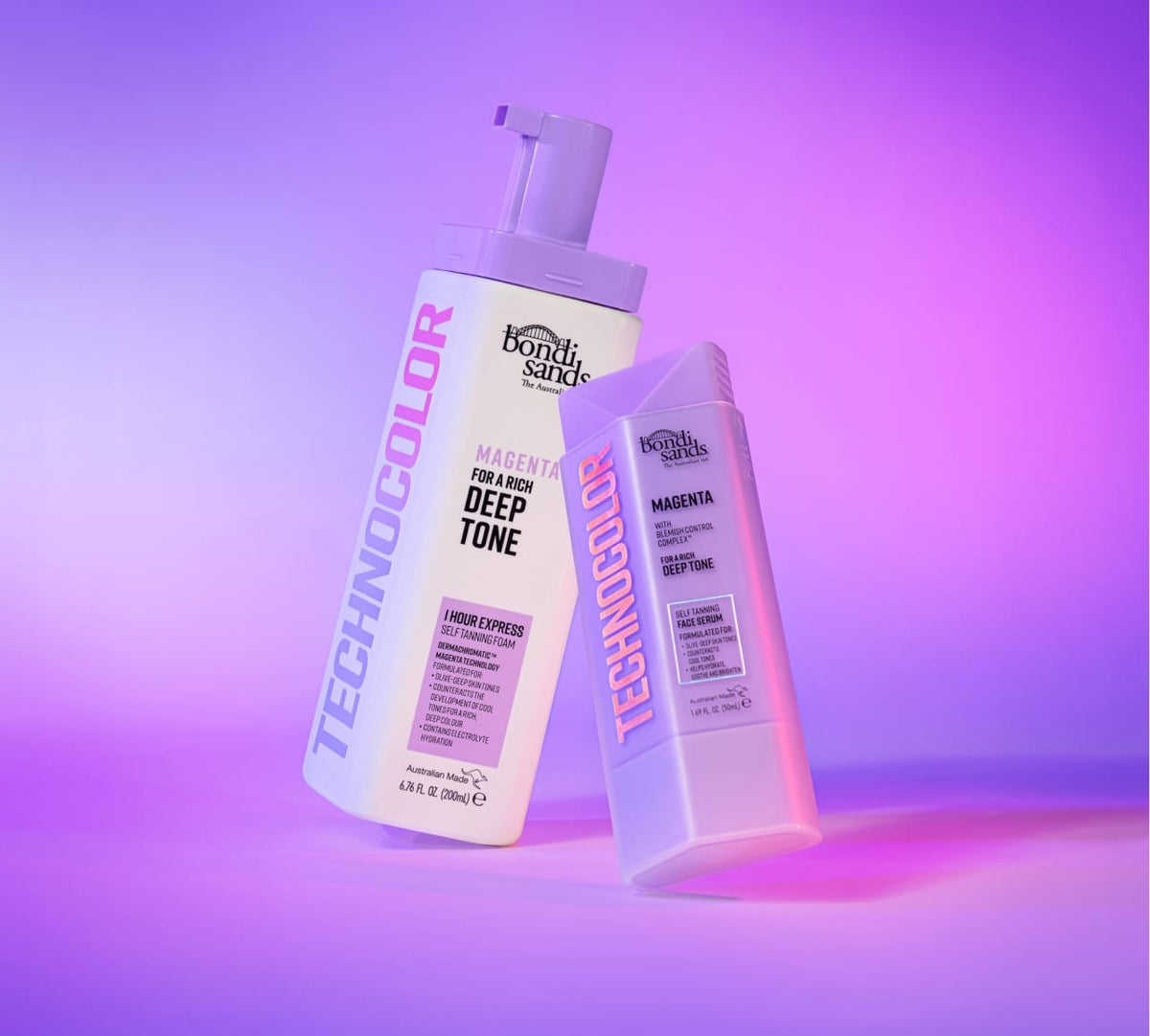 Two bottles of BondiSandsEU Magenta Technocolor Self Tanning Face Serum are shown on a pink and purple background. Ideal for olive-deep skin tones, they provide a natural-looking glow for your face.
