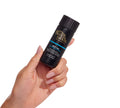 A hand with manicured nails holds a black bottle of BondiSandsEU Self Tan Drying Powder against a white background—an essential step in your tanning routine for a flawless finish.
