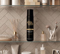 The BondiSandsEU Glow & Go Bundle is displayed on a bathroom shelf among makeup brushes, skincare bottles, and beauty accessories, promising a radiant glow against a backdrop of tiled walls.