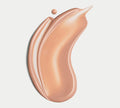 A smooth, creamy swipe of BondiSandsEU Face SPF 50+ Tinted Everyday Sunscreen Fluid with a dewy finish on a white background, and a small drop of the same product near the top edge of the streak.