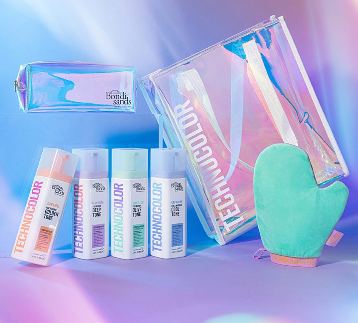 The BondiSandsEU Sapphire Technocolor 1 Hour Express Self Tanning Foam is shown with a clear iridescent tote, matching zip pouch, and green tanning mitt on a pastel rainbow background for a flawless natural glow.