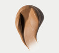 A creamy, caramel-brown layer of BondiSandsEU's Ultra Dark Aero Self Tanning Routine Bundle is swiped on a white surface, revealing its rich, smooth texture and a soft gradient from deep to light bronze.