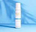 A white and blue bottle of BondiSandsEU Self Tan Eraser stands upright on a blue surface, casting a shadow against a textured blue background.