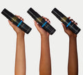 Three hands with different skin tones hold up a black bottle of BondiSandsEU Ultra Dark Self Tanning Foam, featuring strong tanning actives, against a plain white background.