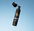A black BondiSandsEU bottle of Light-Medium Self Tanning Routine Bundle foam with a pump and floating cap appears against a blue gradient. The label highlights its light/medium tone and coconut scent—ideal for your self-tanning bundle.