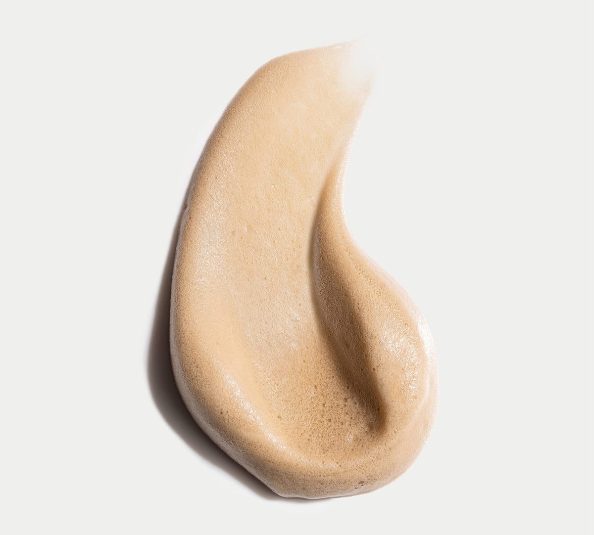 A swirl of light brown, foamy BondiSandsEU Liquid Gold Self Tanning Routine Bundle, with a smooth, airy texture, is spread in a teardrop shape on a white background.