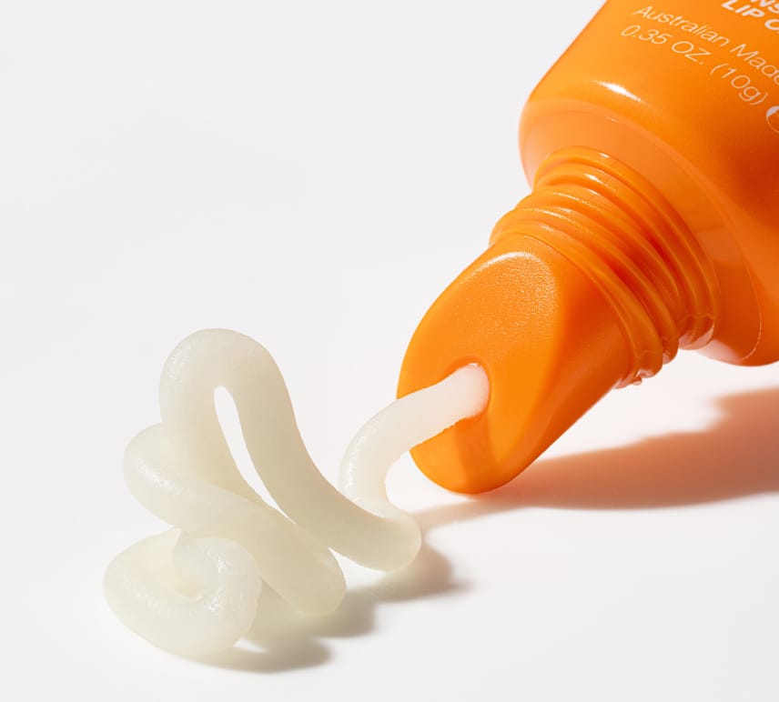 Close-up of an orange tube dispensing clear gel onto a white surface. BondiSandsEU Mango SPF 50+ Lip Balm provides high sun protection, perfect for any skincare or lip care routine.