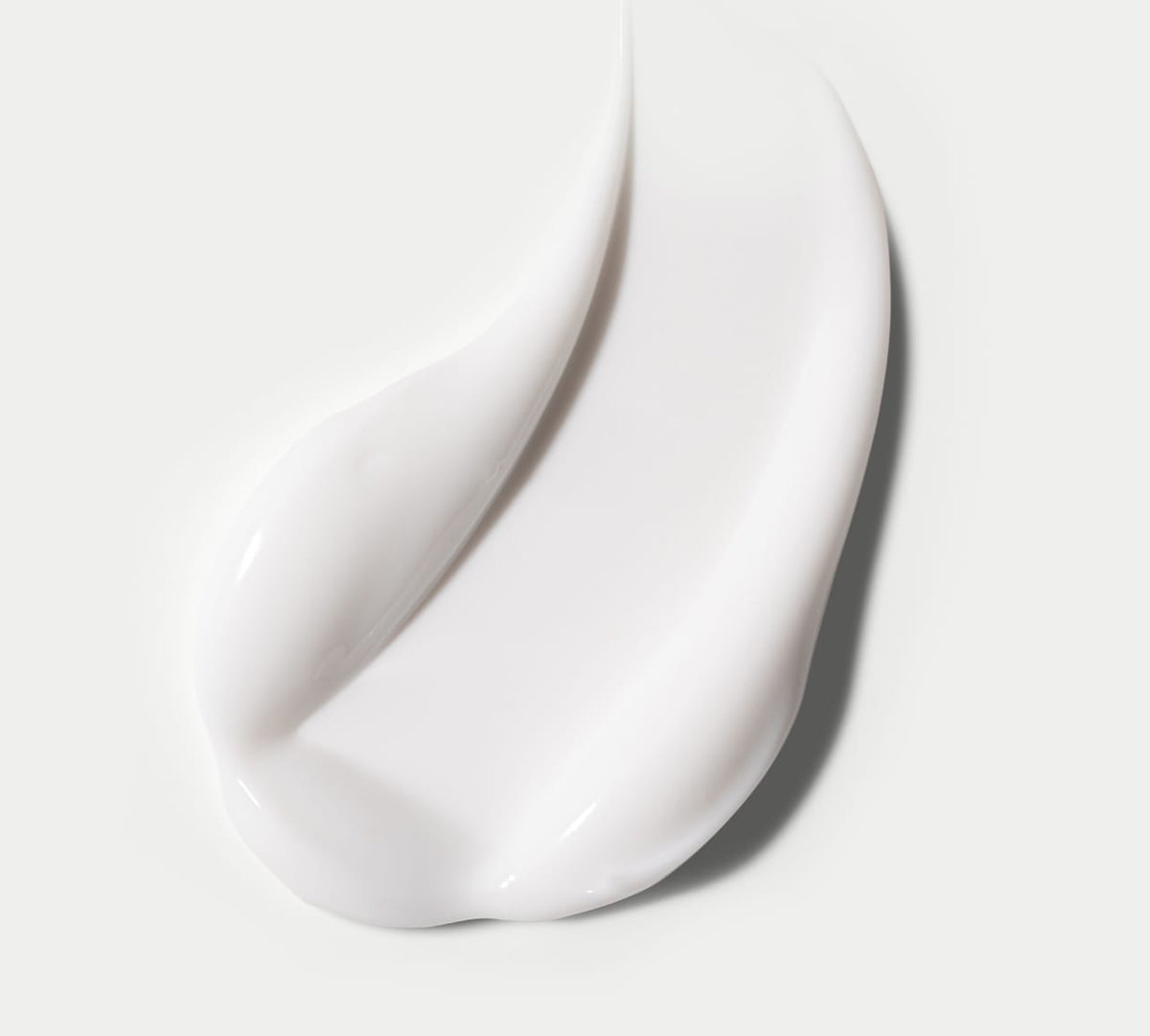 BondiSandsEU Gradual Self Tanning Face Lotion is shown as a smooth, white smear on a light gray background, highlighting its glossy texture and soft curves; dermatologist approved and non-comedogenic.