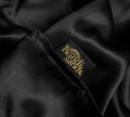 A close-up of the BondiSandsEU Self Tanning Pillow Protector, featuring black satin fabric and a stitched black label with Bondi Sands in gold, designed for mess-free tanning and preventing tan transfer.
