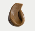 A smooth, brown, creamy substance—resembling BondiSandsEU Ultra Dark Self Tanning Foam—is swirled in an irregular teardrop shape on a white background.