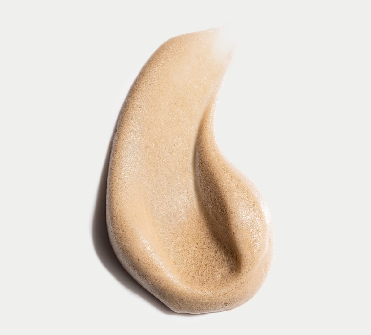 A close-up of BondiSandsEU Liquid Gold Self Tanning Foam on a white background reveals its smooth, airy texture with bubbles and hints at the radiant golden glow this self tanning mousse provides.