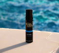A bottle of BondiSandsEU Ultra Dark Self Tanning Foam stands upright by a poolside, with a blurred blue swimming pool in the background, perfectly showcasing this self tanner rich in tanning actives.