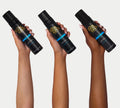 Three hands of varying skin tones each hold a black bottle of BondiSandsEU Dark Self Tanning Foam, featuring gold and blue labels, set against a plain light background.