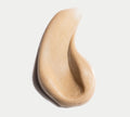 A swatch of beige, creamy mousse with a smooth, airy look—evoking the BondiSandsEU Bondi Get Glowing Tanning Routine 4-piece Gift Set—spread in an abstract curved shape on a white background.