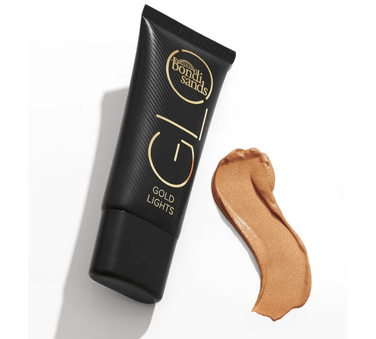 A black tube of BondiSandsEU Gold GLO Lights rests on a white surface beside a smear of shimmery golden-bronze liquid, ideal for creating a radiant highlighter glow.