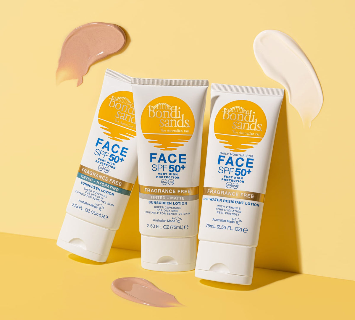 Three BondiSandsEU SPF 50+ Everyday Hydrating Tinted Face Lotion tubes—hydrating, tinted, and fragrance-free—are shown on a yellow surface with beige and pink swatches arranged around them.