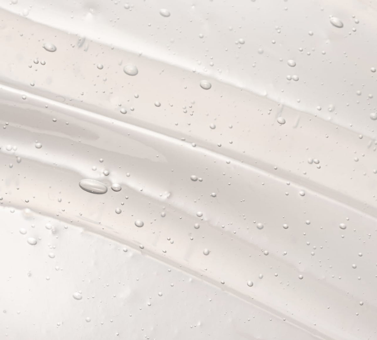 A clear, glossy gel with tiny air bubbles swirled in smooth layers on a white background—ideal for BondiSandsEU’s Self Tan Remover Gel Eraser.