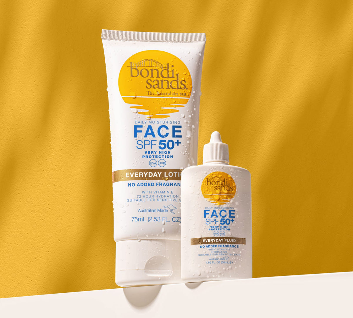 BondiSandsEU Face SPF 50+ Everyday Sunscreen Fluid, in a tube and bottle, is shown against a yellow backdrop with water droplets. This daily sunscreen offers non-greasy sun protection and moisturizing benefits for your face.