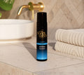 The BondiSandsEU Express Self Tanning Routine Bundle rests on a beige counter by a white sink and towels, sunlight streaming in—ideal for anyone wanting to add an express tanning bundle to their self care routine.