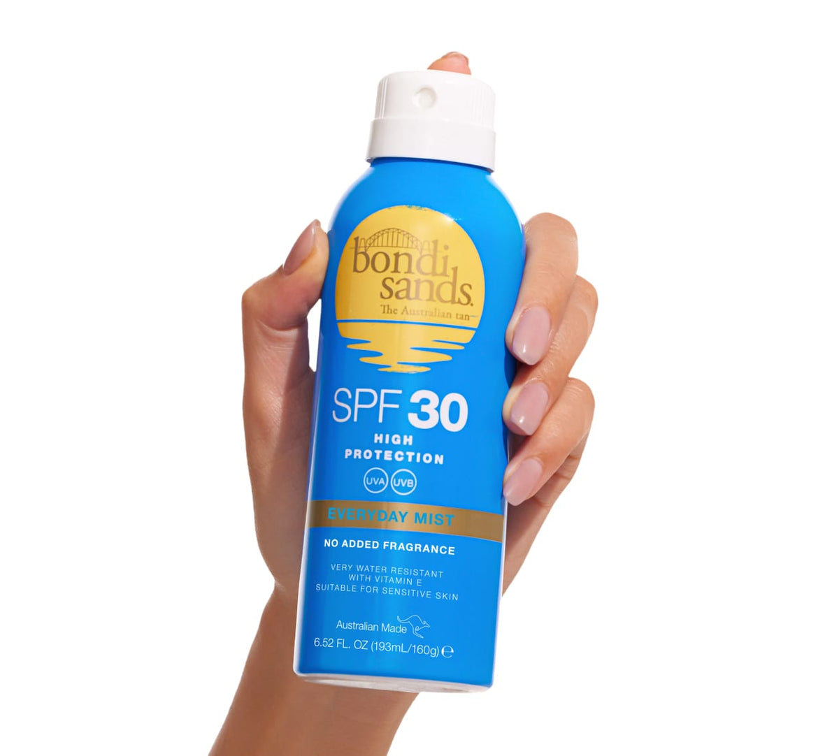 A hand holds a blue can of BondiSandsEU SPF 30 Everyday Sunscreen Aerosol Mist with yellow and white text and a blue cap, set against a plain white background.