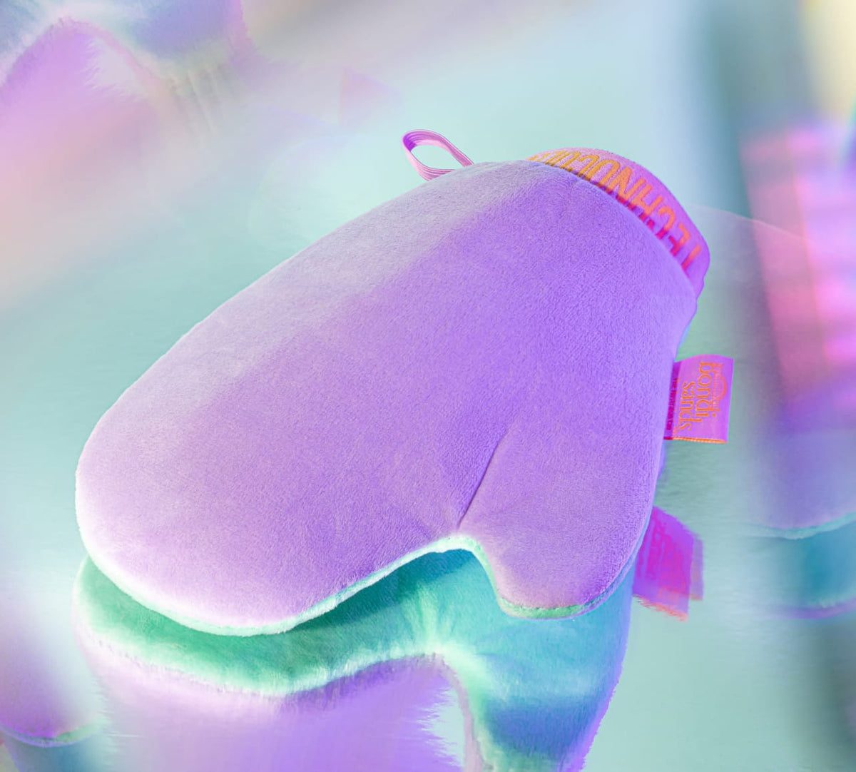 The BondiSandsEU Technocolor Deluxe Self Tanning Application Mitt is a soft, purple mitt with a pink and yellow loop—ideal for applying self tanning products for a streak-free tan.