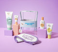 The BondiSandsEU Brightening Besties Gift Set features Vitamin C serum, cleansers, sunscreen, a "Brightening Besties" cosmetic bag, and an "Everyday Skincare" headband, all displayed on a pink surface.
