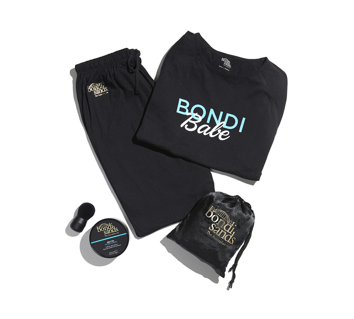 A flat lay of Bondi Babe Tanning PJs by BondiSandsEU—black shirt with “Bondi Babe”, black pants, self tanning sheet protector, small jar, makeup applicator, and black pouch—all on a white background.