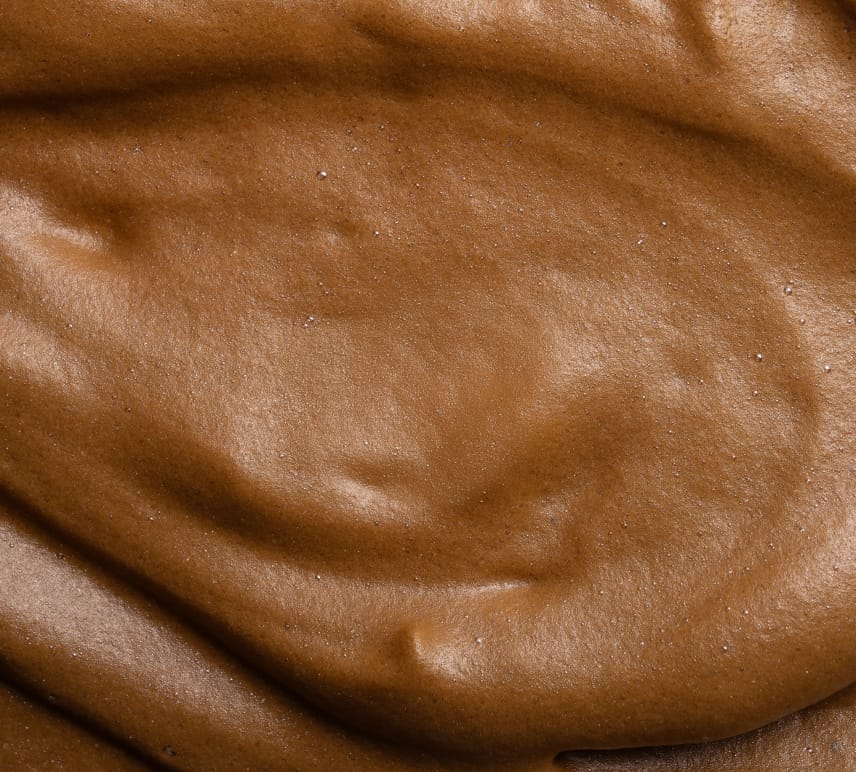 Close-up of BondiSandsEU Express Aero Self Tanning Mousse, featuring a smooth, creamy texture and deep bronze color with glossy swirls and peaks, resembling rich chocolate mousse.