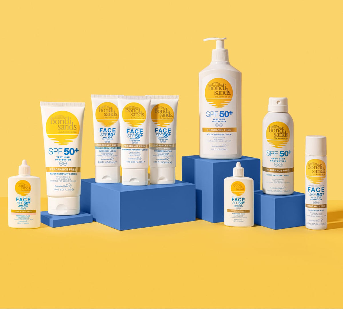 Nine BondiSandsEU sunscreen products with yellow and blue labels are displayed on blue blocks against a yellow background, including everyday bottles, tubes, and the Face SPF 50+ Tinted Everyday Sunscreen Fluid.