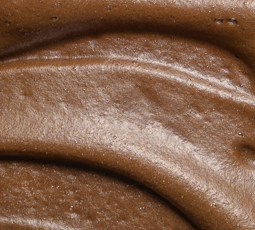 Close-up of BondiSandsEU Express Aero Self Tanning Mousse with a smooth, creamy texture and deep bronze gloss, featuring slight bubbles and swirled surface patterns.