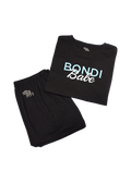 The BondiSandsEU Bondi Babe Short Tanning PJs feature a folded black T-shirt with “Bondi Babe” in blue and white, paired with matching black shorts adorned with a small Bondi Sands logo on the left leg. Displayed together on a white background, this loungewear set is perfect for relaxing at home or slipping into after applying self tan.