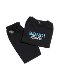A folded black T-shirt featuring "BONDI Babe" printed in blue and white, paired with matching black pants, both displayed on a white background—BondiSandsEU’s Bondi Babe Tanning PJs, the ideal self-tan protector for your nighttime routine.