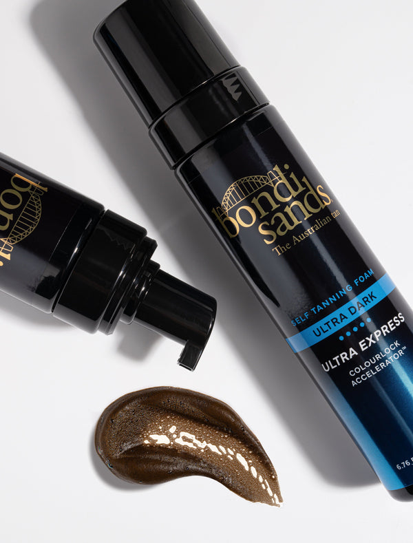 Two black bottles from the Bondi Sands Europe Ultra Express Self Tanning Foam & Application Mitt Bundle rest on a white surface, one with a pump. A streak of dark tan mousse shows the results possible when used with the included mitt.