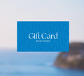 A blue BondiSandsEU Gift Card with white text appears against a blurred ocean and coastline background, ideal for email delivery.