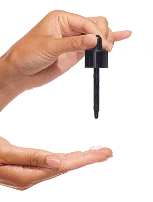 A hand holds a black dropper above an open palm, dispensing clear liquid—like BondiSandsEU Self Tan Drops Dark—onto a small amount of white cream on the fingers, set against a white background.