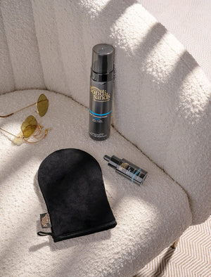 The BondiSandsEU Self Tan Drops Dark, tanning mitt, dropper bottle, and sunglasses sit on a textured cream chair in sunlight—everything you need for a flawless Australian-inspired tan.