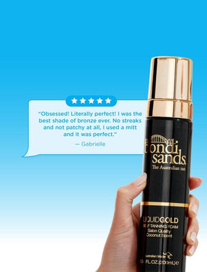 A hand holds a BondiSandsEU Self Tanning Foam Liquid Gold bottle against a blue background. Above, a customer review praises its even color and easy application.