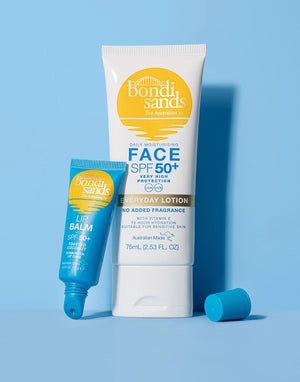 Two BondiSandsEU products on a blue background: the SPF 50+ Lip Balm Toasted Coconut (10g) upright, next to a larger white tube of SPF 50+ face lotion (75ml) leaning slightly right.