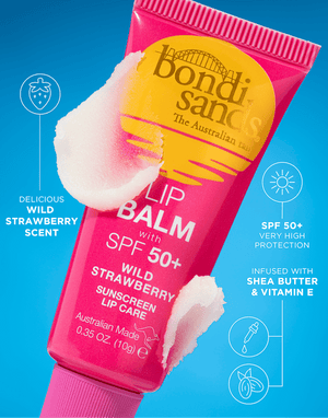 A pink tube of BondiSandsEU SPF 50+ Lip Balm Wild Strawberry with nourishing Shea Butter sits on a blue background amid white balm smears, with scent, SPF 50+, and ingredients highlighted in text.