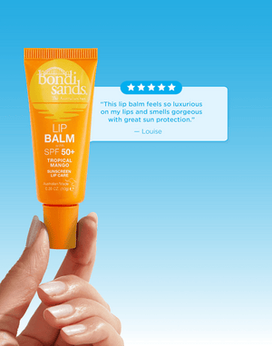 A hand holds a yellow tube of BondiSandsEU SPF 50+ Lip Balm Tropical Mango against a blue background, while a customer review praises its luxurious feel and superior sun protection.