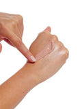 A hand with light skin tone applies a streak of BondiSandsEU Face SPF 50+ Tinted & Matte Sunscreen Lotion to the back of the other hand, against a white background.